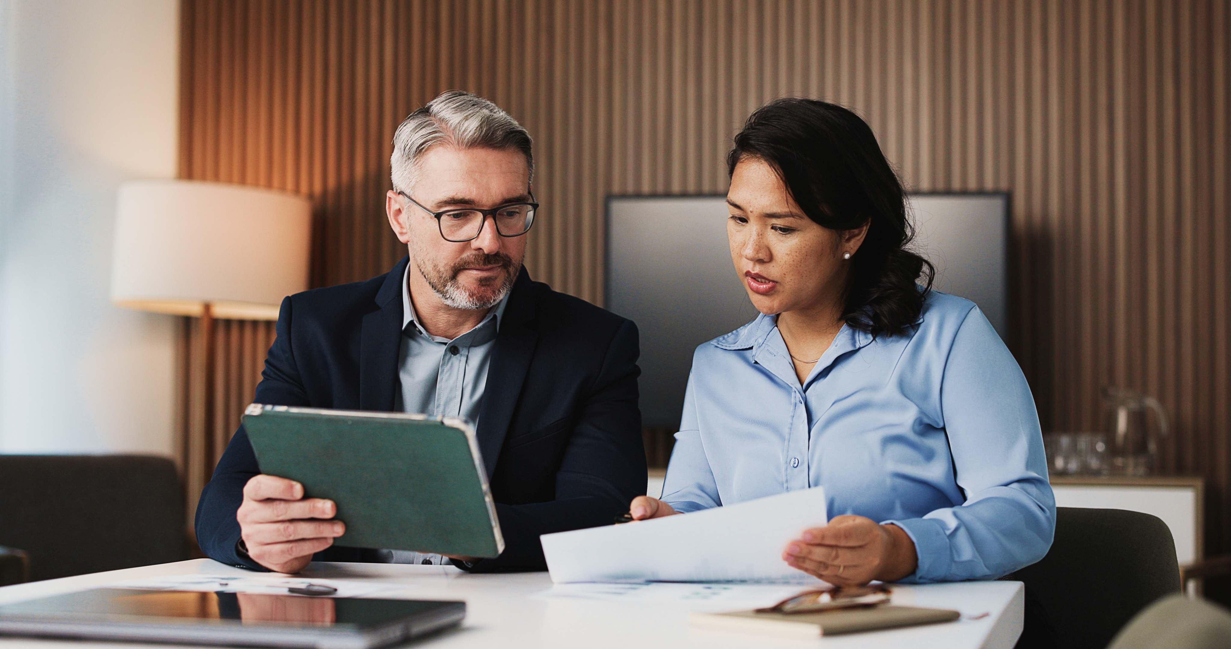 Paperwork, tablet and business people in office with discussion for finance report for budget planning. Collaboration, digital technology and manager with financial advisor for investment deal review
