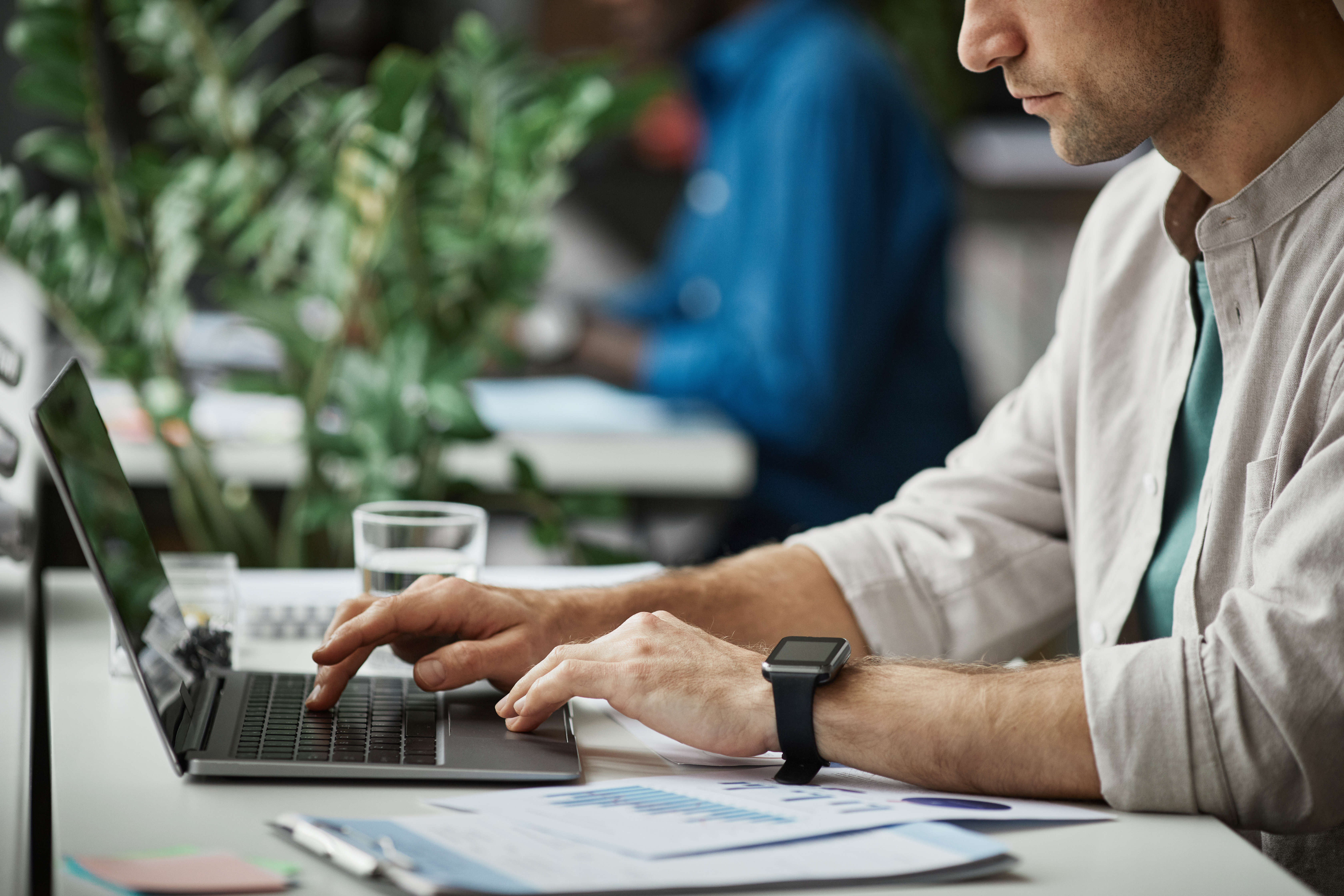 Side view close up of adult man using laptop while enjoying work in office